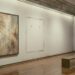 An empty museum gallery: one large abstract painting hangs on a pale wall, and beside it at the same height a clean rectangle of unfaded wall with two bare picture hooks where a painting of the same size hung for decades.